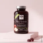 En dåse med Hair Volume gummies på en lyserød platform med 2 gummies foran.