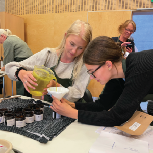 Urteskole 29 Til kvinder, der eksperimenterer med urter ved et arrangement på en urteskole, hvor de lærer om og arbejder med planter.
