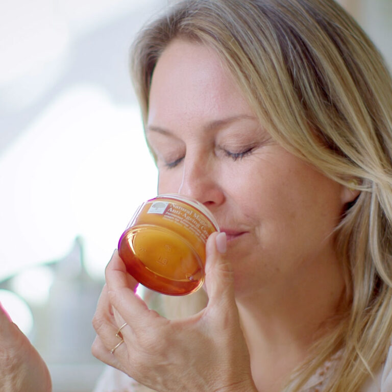 Kvinde med lukkede øjne dufter til Natural Magic™ Anti-Ageing Cream som del af sin hudplejerutine.