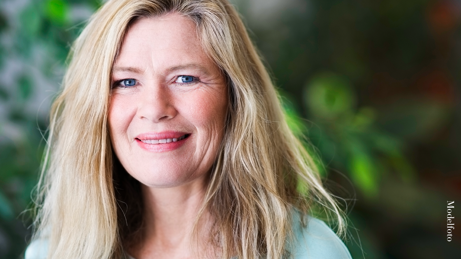 “Jeg drømte om at gøre noget ved min bekymringsrynke” 6 Smilende kvinde med lyst hår ser direkte ind i kameraet foran en grøn baggrund.